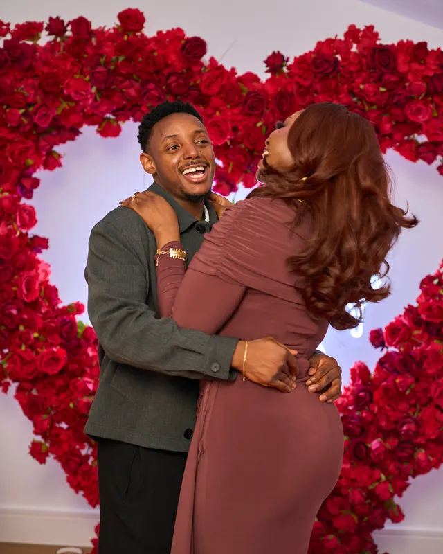 A couple embracing in front of red roses