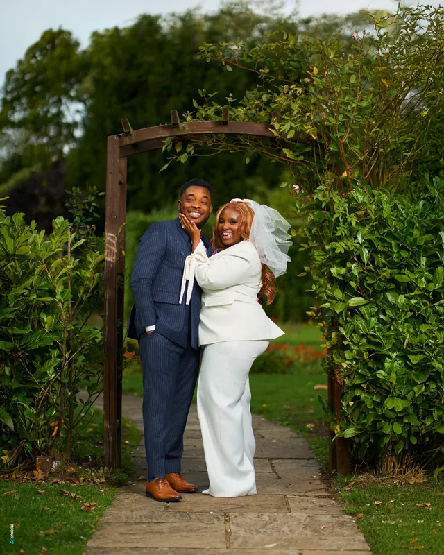 Newlyweds embracing beneath a garden arch