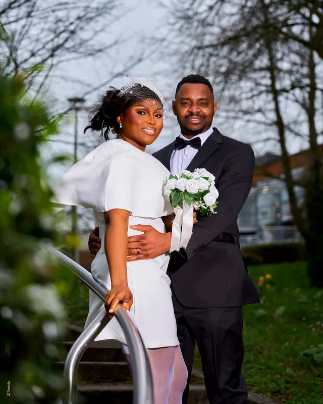 A couple holding their bouquet on a garden bridge