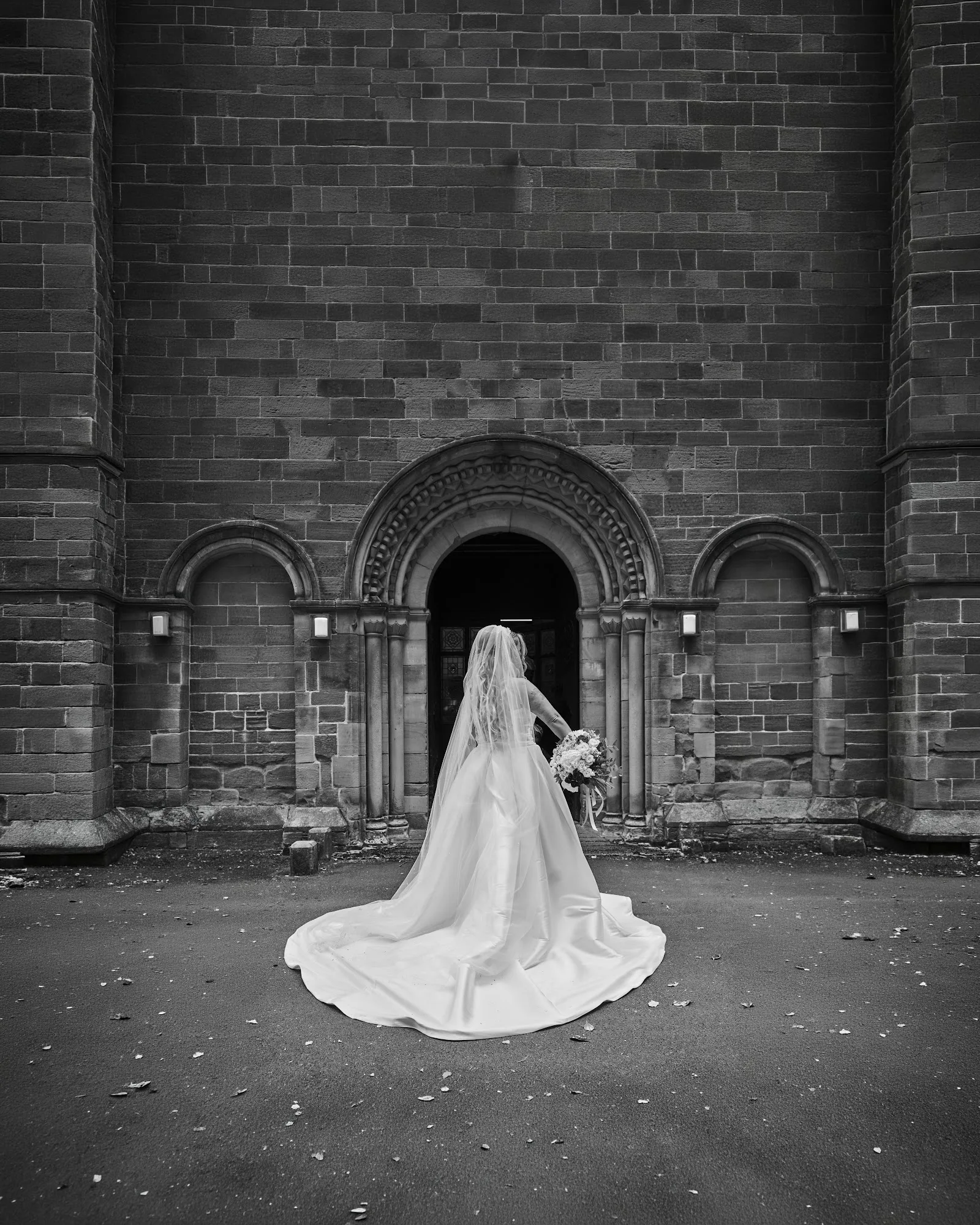 A black and white bridal portrait outside a stone church
